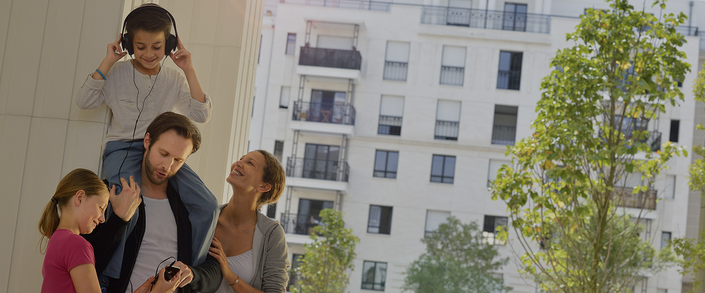 Famille souriante devant un immeuble